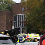 Manchester Synagogue knife Attack Leaves 2 Dead, 3 Seriously Injured on Yom Kippur. Two people have died and three others are in serious condition after a stabbing and car attack outside the Heaton Park Hebrew Congregation Synagogue in Manchester on Yom Kippur. Greater Manchester Police (GMP) said they were called shortly after 9:30 a.m. on Thursday, Oct. 2. A car had been driven into worshippers, and a man and a security guard were stabbed. Police confirmed two victims had died. The suspected attacker was shot by GMP firearms officers and is also believed to be dead, though confirmation is pending due to suspicious items on his body. A bomb disposal unit was deployed. Authorities said a large number of worshippers were inside the synagogue during the attack. GMP praised a bystander whose quick action prevented the attacker from entering the building. Prime Minister Keir Starmer called the incident “all the more horrific” given its timing on Yom Kippur. King Charles also expressed shock and praised the swift response of emergency services. Police said the attack has caused “significant shock and fear” across communities. Security has been increased at synagogues throughout Greater Manchester.